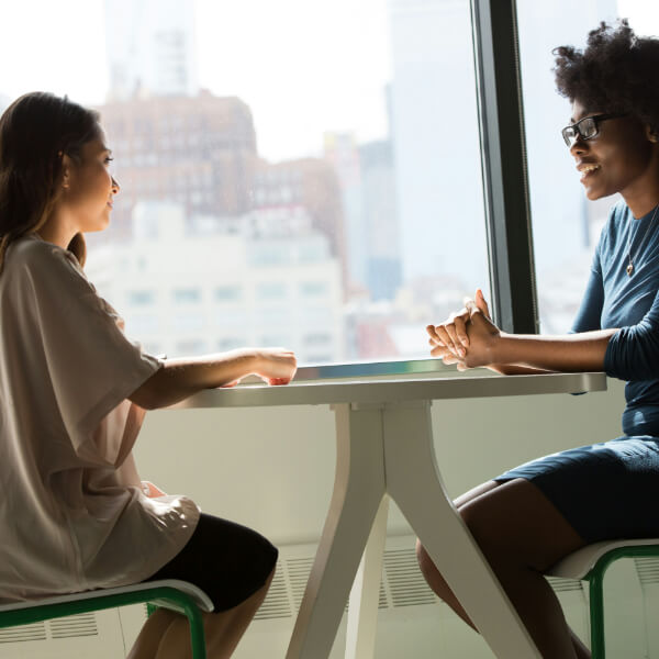 Two ladies talking over table