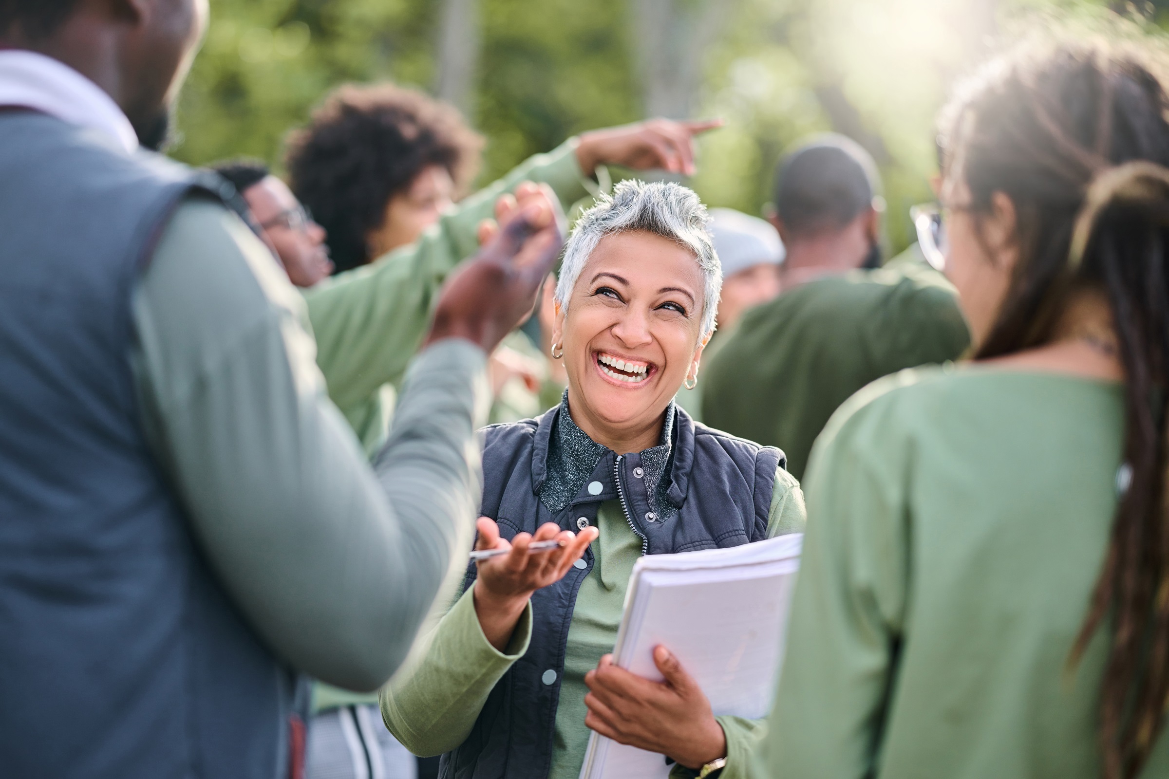 Woman smiling and speaking to two people at an outdoor event.